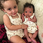 Kyomi is registered to the contest to win money with this photo: baby, toddler, child, siblings, matching_outfits, ladybug_pattern, curly_hair, newborn, couch, indoor, smile, holding, cute, family, infant, clothing, person, skin, face, seated