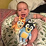 Kaiden is registered to the contest to win money with this photo: baby, smiling, plush_toys, pillow, indoor, child, happy, infant, cute, face, person, holding, toy, sitting, legs, foot, fabric, pattern, cozy, bedroom