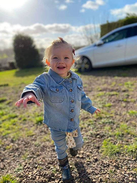 April participe au concours pour gagner de l'argent avec cette photo : baby_toddler_clothing, body_of_water, car, cloud, face, flash_photography, grass, happy, joy, leaf, people_in_nature, person, plant, sky, smile, standing, sunlight, tire, toddler, tree