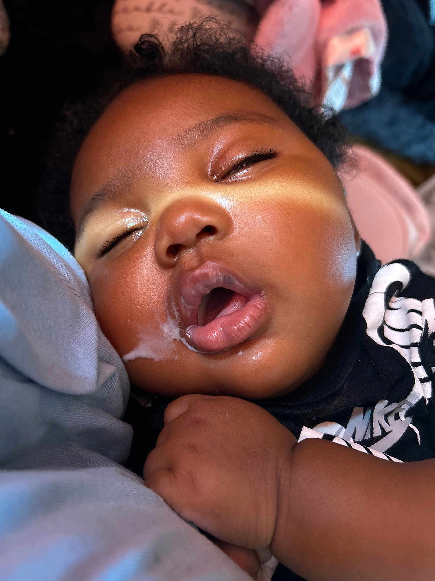 Miyonni Rose is registered to the contest to win money with this photo: baby, sleeping, drool, close_up, face, hand, infant, skin, curly_hair, peaceful, nap, black_clothing, soft_light, indoor, child, portrait, resting, cute, young_child, relaxed
