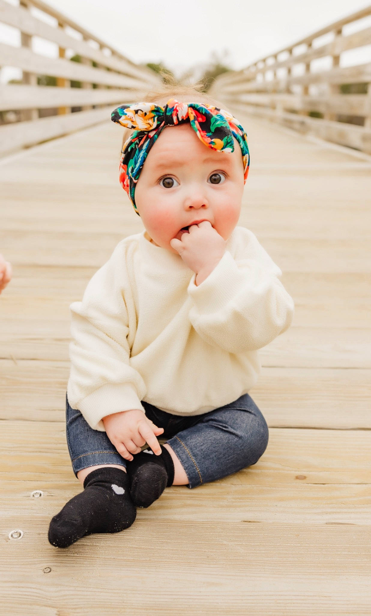 Hazel is registered to the contest to win money with this photo: baby, baby_products, baby_toddler_clothing, beanie, cap, child, clothing, fashion_accessory, floor, flooring, fun, happy, hardwood, headband, headwear, pattern, person, sitting, sleeve, surprise