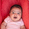baby, chubby_cheeks, couch, cute, eyes, face, happy, indoors, infant, mouth_open, nike_logo, one_person, pink_onesie, portrait, red_cushion, seat, short_hair, skin, smiling, soft_lighting