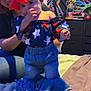 toddler, child, adult, bed, headband, red_bow, jeans, off_shoulder_top, stars_pattern, colorful_tapestry, award_poster, furniture, indoor, person, supporting_hand, blanket, home, smiling, cute, cozy