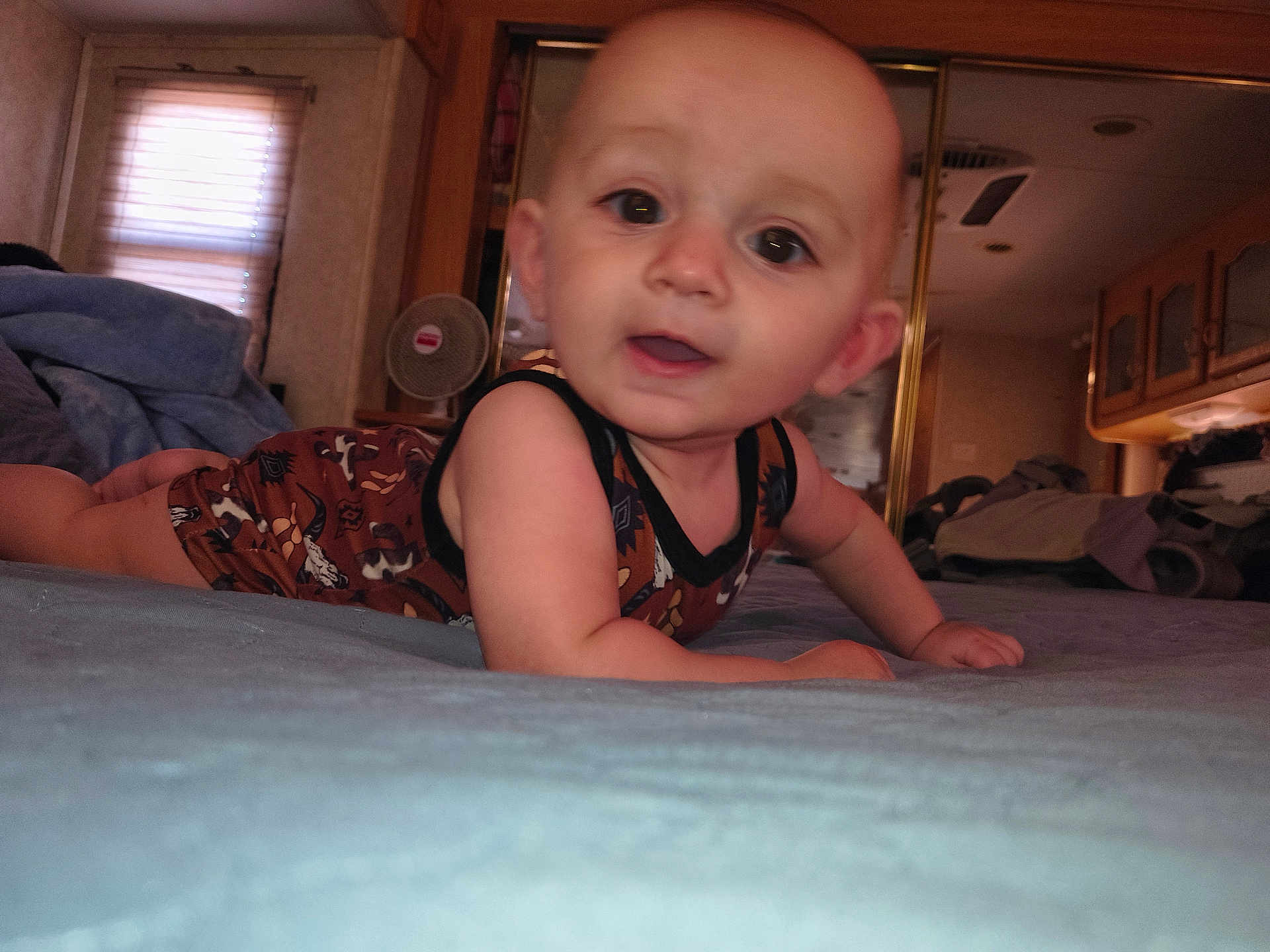 Kolton joined the competition — help win amazing prizes! baby, infant, child, face, eyes, mouth, skin, onesie, cowboy_prints, bed, blanket, crawling, mirror, fan, wardrobe, bedroom, interior, portrait, close_up, smile