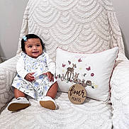 Umber is registered to the contest to win money with this photo: baby, child, infant, smiling, sitting, dress, floral_pattern, bow, hair_accessory, white_shoes, armchair, textured_fabric, pillow, embroidery, woodland_animals, butterflies, milestone_sign, four_months, indoor, happy
