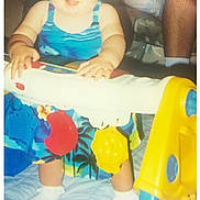 Kay joined the competition — help win amazing prizes! baby, child, toy, walker, blue_clothing, tropical_pattern, smiling, standing, indoor, adult_legs, white_socks, colorful, plastic_toy, photo_scan, flash, vintage_photo, person, happy, playtime, home