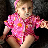 Valencia joined the competition — help win amazing prizes! child, toddler, pacifier, pink_clothing, headband, pajamas, sitting, couch, indoor, holding_hand, cute, baby, portrait, infant, face, blue_eyes, short_hair, hand, comfort, relaxed