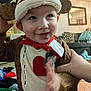 toddler, child, costume, monkey_costume, hat, smile, face, hand, living_room, couch, blanket, pillow, red_heart, plush, clothing, indoors, cute, happy, person, playful
