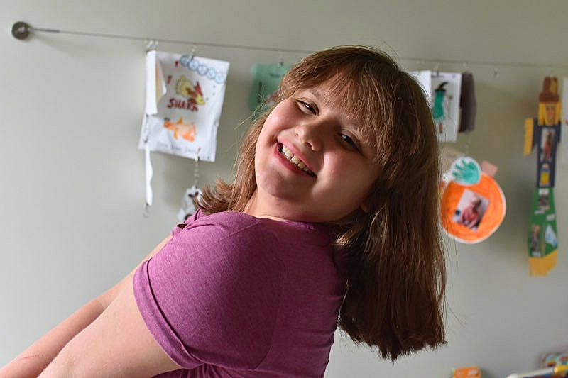 Kaelyn is registered to the contest to win money with this photo: arm, blond, brown_hair, chest, child, clothing, elbow, eyelash, happy, human_leg, jaw, joy, knee, mouth, neck, person, room, smile, t_shirt, thigh