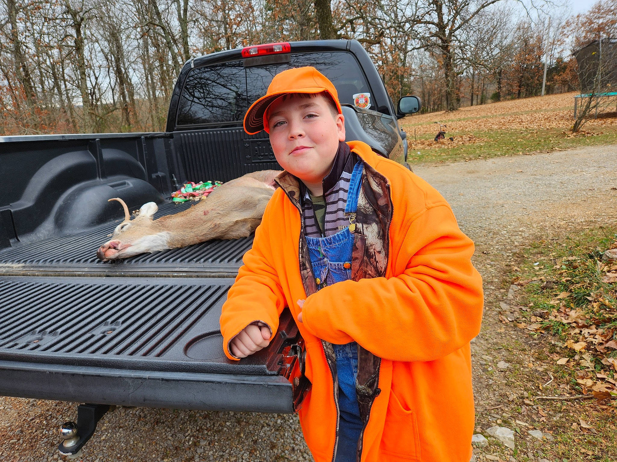 Jesse is registered to the contest to win money with this photo: asphalt, automotive_design, automotive_exterior, automotive_tire, bumper, car, grass, hat, headwear, helmet, hood, jacket, motor_vehicle, person, plant, smile, tire, tree, truck, vehicle