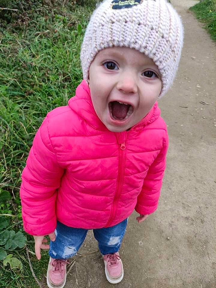 Louana participe au concours pour gagner de l'argent avec cette photo : baby, baby_toddler_clothing, cap, child, clothing, eye, grass, happy, headgear, headwear, knit_cap, lip, magenta, pattern, person, pink, plant, sleeve, smile, toddler