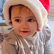 Méa a rejoint le concours — aidez-le/la à gagner de superbes lots ! toddler, child, santa_hat, smiling, indoor, window, soft_lighting, cute, holiday, festive, portrait, baby, face, clothing, gray_dress, hands, happy, young_child, cozy, closeup