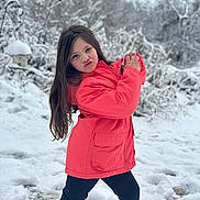 Sophie is registered to the contest to win money with this photo: child, girl, snow, winter, outdoor, playful_pose, coral_jacket, long_hair, leggings, snowy_background, nature, trees, cold_weather, fun, pucker_lips, standing, park, casual_clothing, daylight, smile
