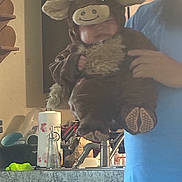 Hudson is registered to the contest to win money with this photo: baby, costume, bull, kitchen, counter, paper_towel, soap_dispenser, person, hand, clothing, fuzzy, cute, indoor, holding, sink, appliance, blue_shirt, face, toy, animal_costume