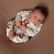 Damari is registered to the contest to win money with this photo: baby, newborn, infant, onesie, teddy_bear_pattern, brown_background, curled_up, feet, hands, face, sleepwear, cute, portrait, lying_down, cozy, soft_texture, bed, skin, expression, newborn_photography