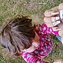 casual, child, cute, daylight, fingernails, flower_pattern, grass, hair, hand, head, holding, interaction, nails, nature, outdoor, person, pink_clothing, playing, skin, young