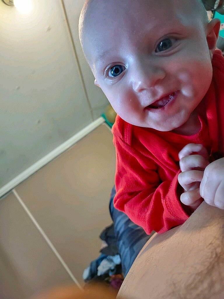 Atlus is registered to the contest to win money with this photo: baby, baby_toddler_clothing, cheek, chest, chin, comfort, eyebrow, flooring, fun, hand, happy, human_leg, iris, lip, mouth, nose, person, skin, smile, thumb