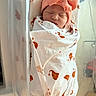 newborn, baby, infant, swaddled, blanket, headband, bow, sleeping, hospital, bassinet, peaceful, wrapped, cute, orange, white, face, person, indoors, soft_light, serene
