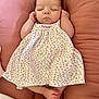 baby, sleeping, infant, dress, floral_pattern, pink, cushion, hands, feet, peaceful, cute, newborn, child, portrait, resting, soft, cozy, indoors, closeup, adorable