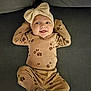 Azalea is registered to the contest to win money with this photo: baby, bow, brown_clothing, child, comfortable, couch, cozy, cute, fabric, happy, headband, indoors, infant, lying_down, paw_prints, person, portrait, relaxed, smiling, soft_lighting