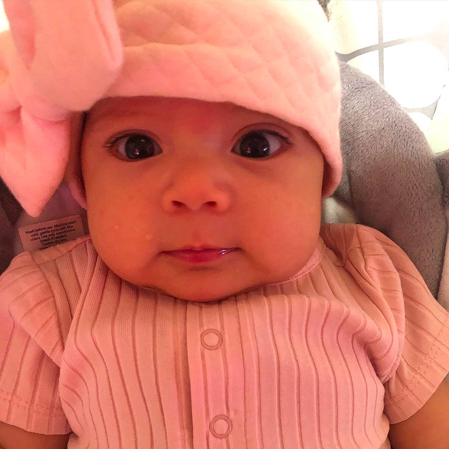 Elsie joined the competition — help win amazing prizes! baby, baby_toddler_clothing, cap, cheek, ear, eye, eyebrow, eyelash, forehead, gesture, head, headwear, human_body, iris, lip, mouth, nose, outerwear, person, pink