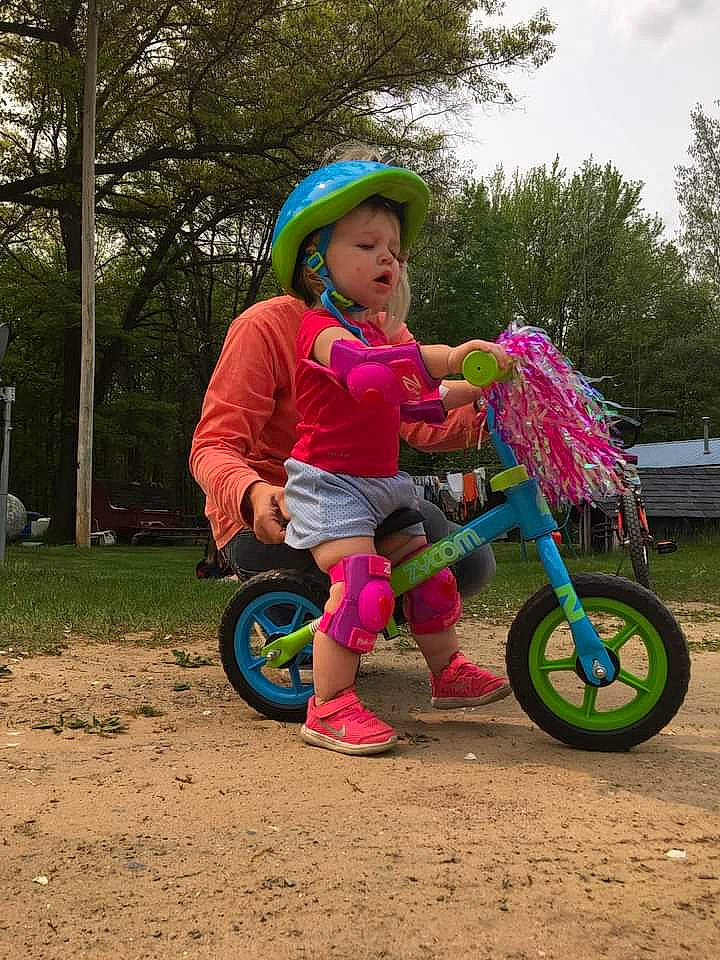 Ansley is registered to the contest to win money with this photo: automotive_tire, automotive_wheel_system, bicycle, bicycle_frame, bicycle_helmet, bicycle_tire, bicycles_equipment_and_supplies, footwear, fun, grass, headwear, jeans, leisure, magenta, person, plant, recreation, sky, tire, toddler