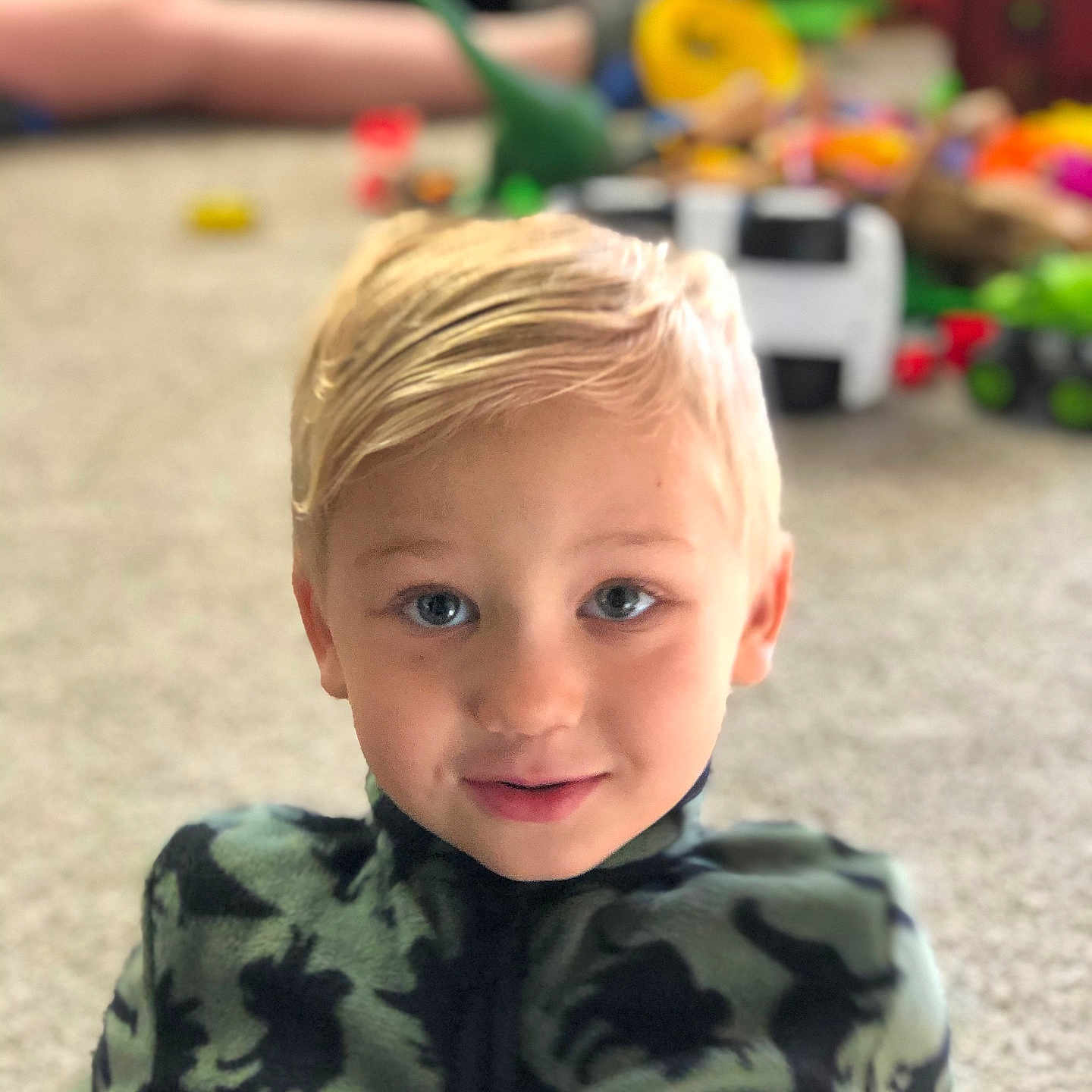 Thalyus is registered to the contest to win money with this photo: background_blur, blonde_hair, blue_eyes, boy, carpet, casual_clothing, child, childhood, cozy, cute, floor, happy, indoor, patterned_jacket, playing, portrait, relaxed, smiling, toy, young