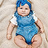 baby, infant, child, portrait, lying_down, blanket, woven_texture, blue_headband, bow, denim_overalls, white_shirt, fashion, indoors, closeup, face, eyes, serious_expression, sitting_pose, cozy, photography
