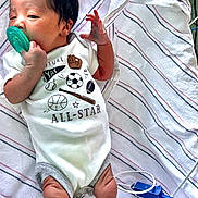 Zhyeed is registered to the contest to win money with this photo: baby, infant, pacifier, hospital_blanket, medical_cables, onesie, sports_graphics, newborn, lying_down, hand, legs, striped_blanket, white_clothing, curious_expression, indoor, medical_device, cute, small, child, human