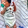 baby, infant, pacifier, hospital_blanket, medical_cables, onesie, sports_graphics, newborn, lying_down, hand, legs, striped_blanket, white_clothing, curious_expression, indoor, medical_device, cute, small, child, human