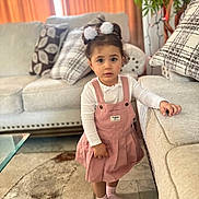 Amaly joined the competition — help win amazing prizes! child, toddler, girl, pink_dress, white_shirt, socks, living_room, couch, pillows, carpet, plant, hair_ties, floor, curious, indoors, furniture, home, portrait, standing, casual