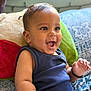 baby, smiling, child, infant, blue_clothing, pillow, indoor, happy, cute, face, portrait, sitting, skin, hand, expression, young_child, background, pattern, cozy, bright