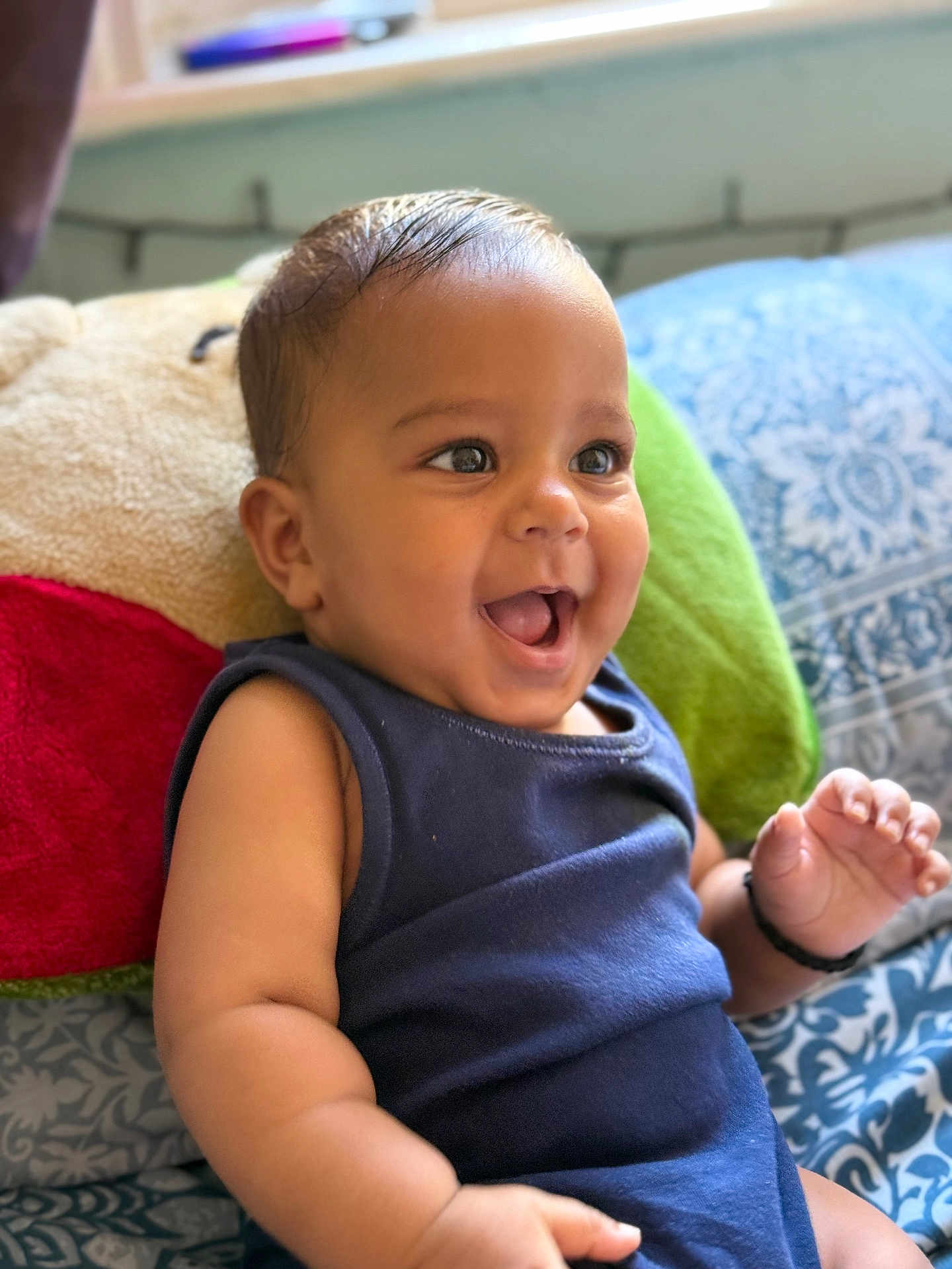 Jaiv is registered to the contest to win money with this photo: baby, smiling, child, infant, blue_clothing, pillow, indoor, happy, cute, face, portrait, sitting, skin, hand, expression, young_child, background, pattern, cozy, bright