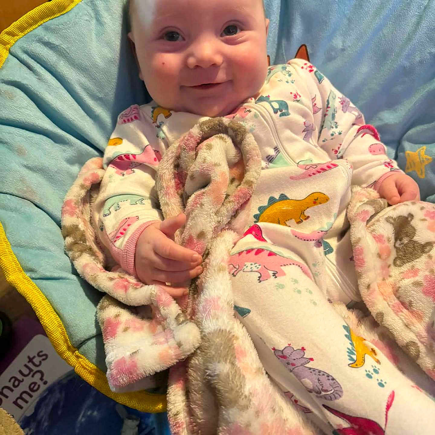 Opal is registered to the contest to win money with this photo: baby, blanket, blue, chair, child, cozy, cushion, cute, dinosaur_print, hand, happy, indoor, infant, onesie, person, pink, portrait, smile, soft_texture, yellow
