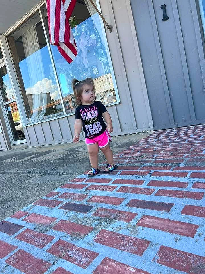 Hazel joined the competition — help win amazing prizes! architecture, building, door, floor, flooring, house, leg, leisure, line, person, plant, red, road_surface, shorts, sidewalk, standing, t_shirt, tints_and_shades, toddler, wall