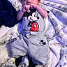 baby, infant, child, portrait, lying_down, blanket, fuzzy_blanket, pajamas, mickey_mouse, beanie, black_hat, gray_clothing, sleeping, awake, hands, face, indoor, cozy, close_up, cute