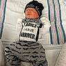Kashtyn is registered to the contest to win money with this photo: newborn, baby, sleeping, portrait, indoor, bed, blanket, striped_bedding, hat, clothing, mustache_pattern, onesie, pajamas, socks, cozy, peaceful, infant, face, text_on_clothing, photography