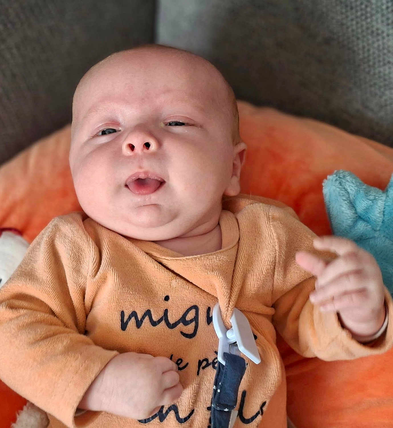 Andrew a rejoint le concours — aidez-le/la à gagner de superbes lots ! baby, infant, face, head, eyes, mouth, cheeks, onesie, orange_onesie, pacifier_clip, hand, pillow, plush_toy, couch, blanket, drool, closeup, portrait, relaxing, nursery