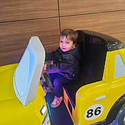 Matthew joined the competition — help win amazing prizes! child, cute, floor, fun, indoor, jacket, kid, lighting, number_86, play, portrait, seat, seat_belt, sneakers, steering_wheel, toddler, toy_car, vehicle, wooden_wall, yellow_car