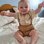 Emrys joined the competition — help win amazing prizes! arms_raised, baby, bed, blue_wall, child, cute, feet, furniture, happy, head, indoor, person, polka_dot_shirt, portrait, shorts, sitting, smiling, suspenders, toothy_grin, white_bedding