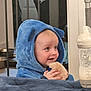 baby, baby_bottle, baby_clothing, blue_hoodie, child, cozy, cushion, cute, fluffy_toy, happy, home, indoor, infant, person, playful, portrait, seated, smiling, soft_toy, young_child