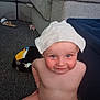 Emrys is registered to the contest to win money with this photo: baby, blue_eyes, carpet, child, cloth, couch, cute, diaper, face, furniture, headwear, indoor, living_room, person, playful, plush_toy, skin, smiling, toddler, toucan