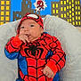 baby, child, costume, spiderman, red, blue, couch, cushion, soft, indoor, portrait, face, hand, fingers, cityscape, cartoon, superhero, cute, smiling, infant