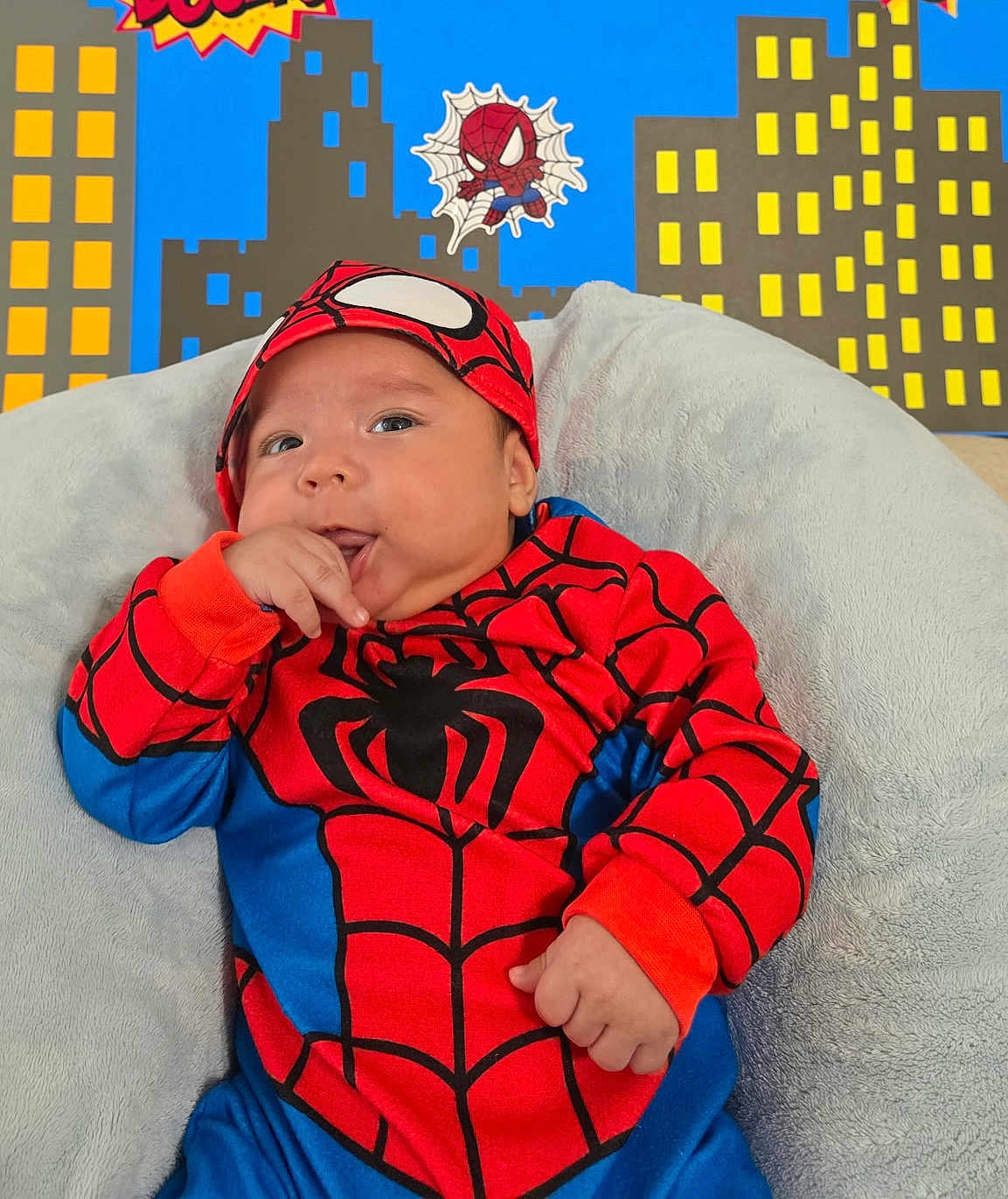 Oliver joined the competition — help win amazing prizes! baby, child, costume, spiderman, red, blue, couch, cushion, soft, indoor, portrait, face, hand, fingers, cityscape, cartoon, superhero, cute, smiling, infant