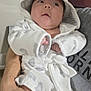 baby, infant, hooded_robe, white_clothing, cute, person, adult_hand, indoor, soft_texture, calm, small_face, wearing_clothes, newborn, portrait, child, human, holding, looking_away, cozy, cute_outfit