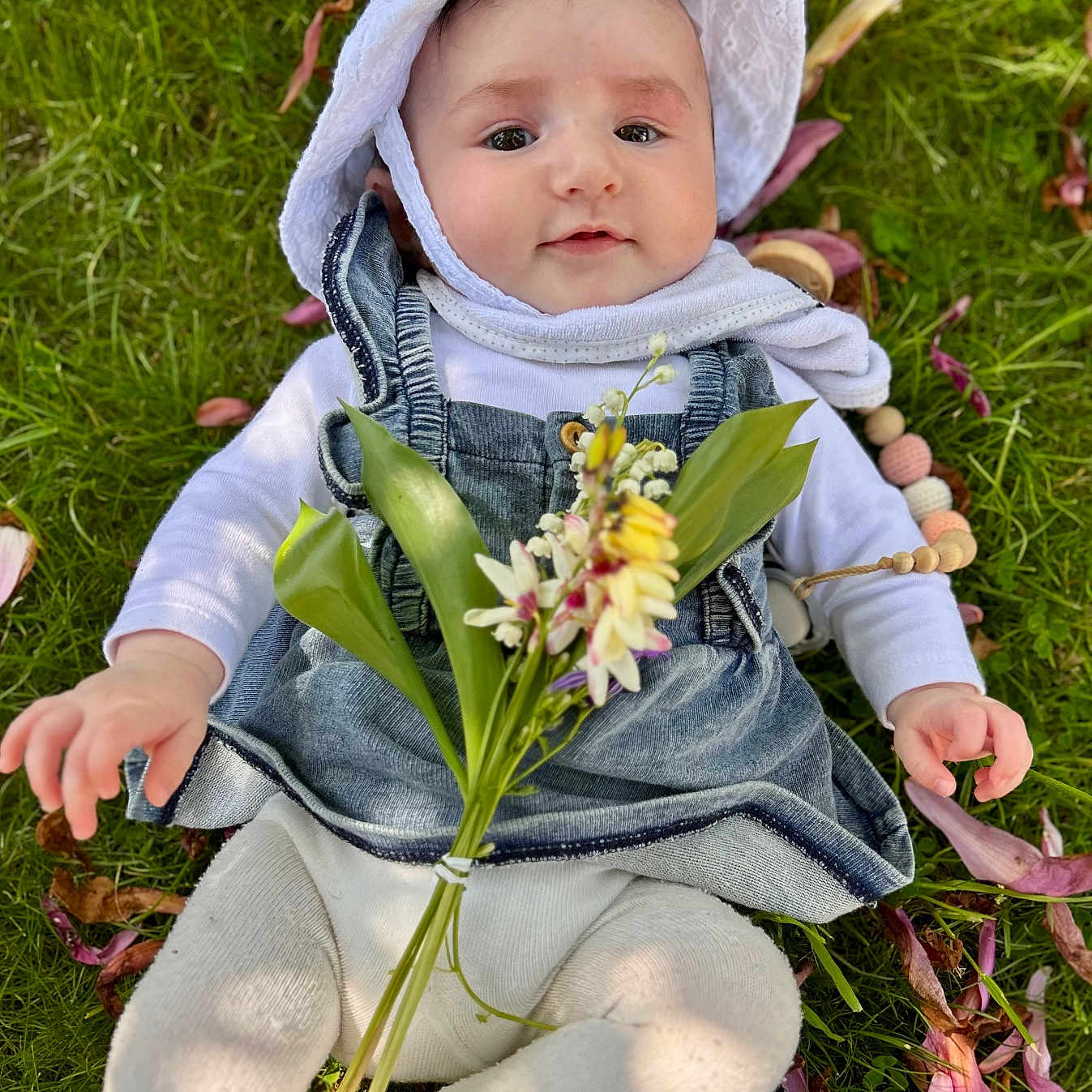 Aliénor participe au concours pour gagner de l'argent avec cette photo : baby, bonnet, cap, clothing, coat, face, flower, flowerarrangement, grass, hat, head, jacket, jeans, leaf, pants, person, petal, photography, plant, portrait