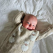 Armand participe au concours pour gagner de l'argent avec cette photo : baby, smiling, sweater, sheep_pattern, blanket, cozy, infant, cute, happy, lying_down, child, soft_texture, knitwear, warm, portrait, cheerful, face, head, indoor, relaxed