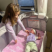 Skylan joined the competition — help win amazing prizes! child, baby, sibling, crib, playpen, blanket, pink_blanket, headband, soft_toy, pajamas, bassinet, mesh_side, curtain, window, mobile, interaction, smile, hand, indoor, nursery