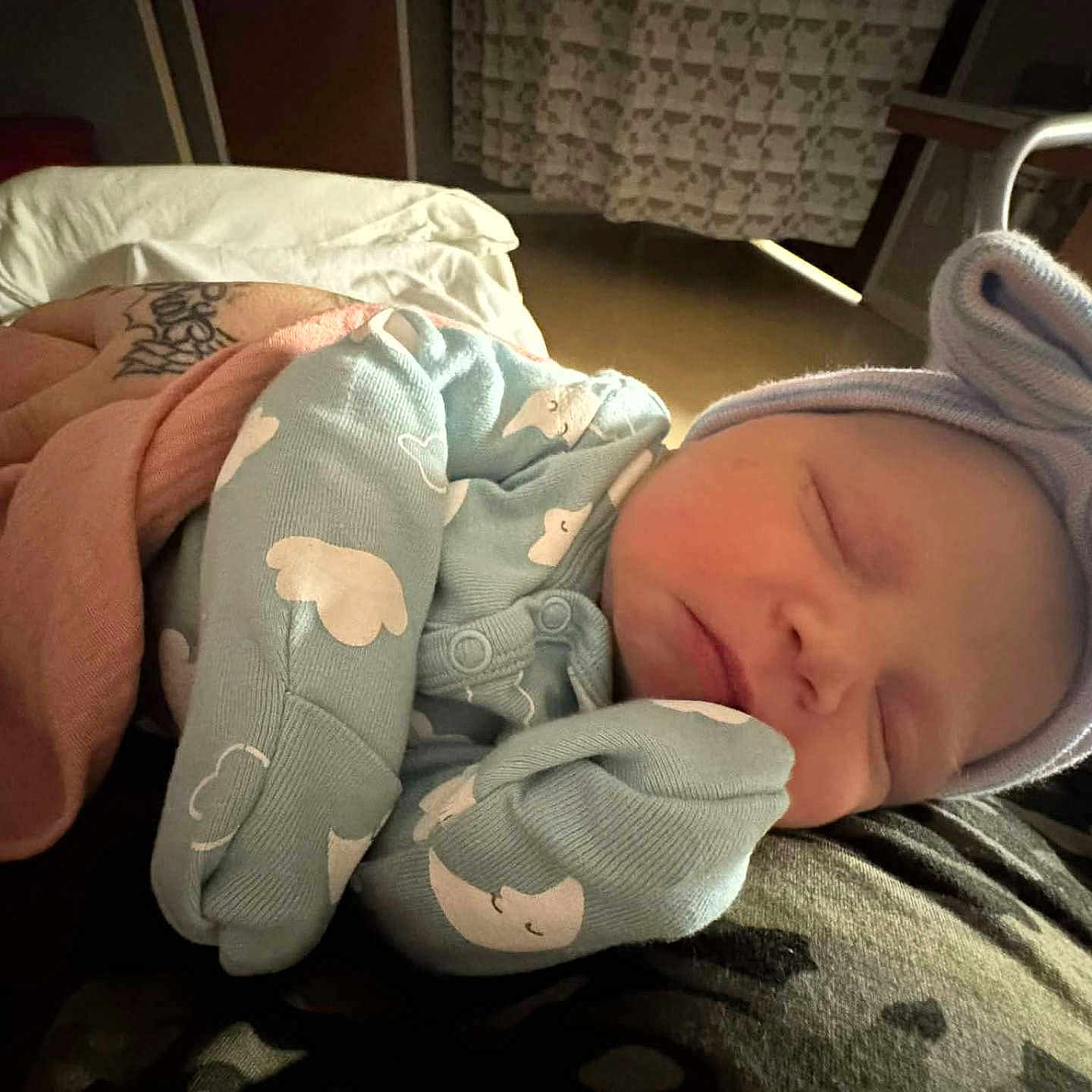Azariah is registered to the contest to win money with this photo: arm, baby, blanket, bow, clothing, cloud_pattern, cozy, cute, hat, indoor, infant, nap, newborn, onesie, peaceful, person, resting, sleeping, soft_lighting, tattoo