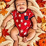 autumn, baby, blanket, child, cozy, fall, family_photo, happy, indoor, infant, knitted_blanket, lying_down, maple_leaves, photography, portrait, pumpkins, red_clothing, seasonal, smiling, star_pattern